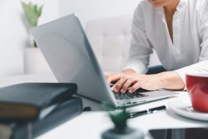 Social media day concept. Female freelancer starting working day early in morning drinking coffee in living room for website with using modern laptop computer. Businesswoman working in home office.